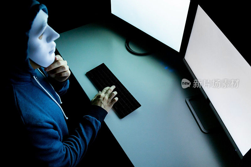 Top view of male hacker in mask under hood用电脑黑进系统并试图犯下电脑犯罪- hacker and computer threat crime概念。